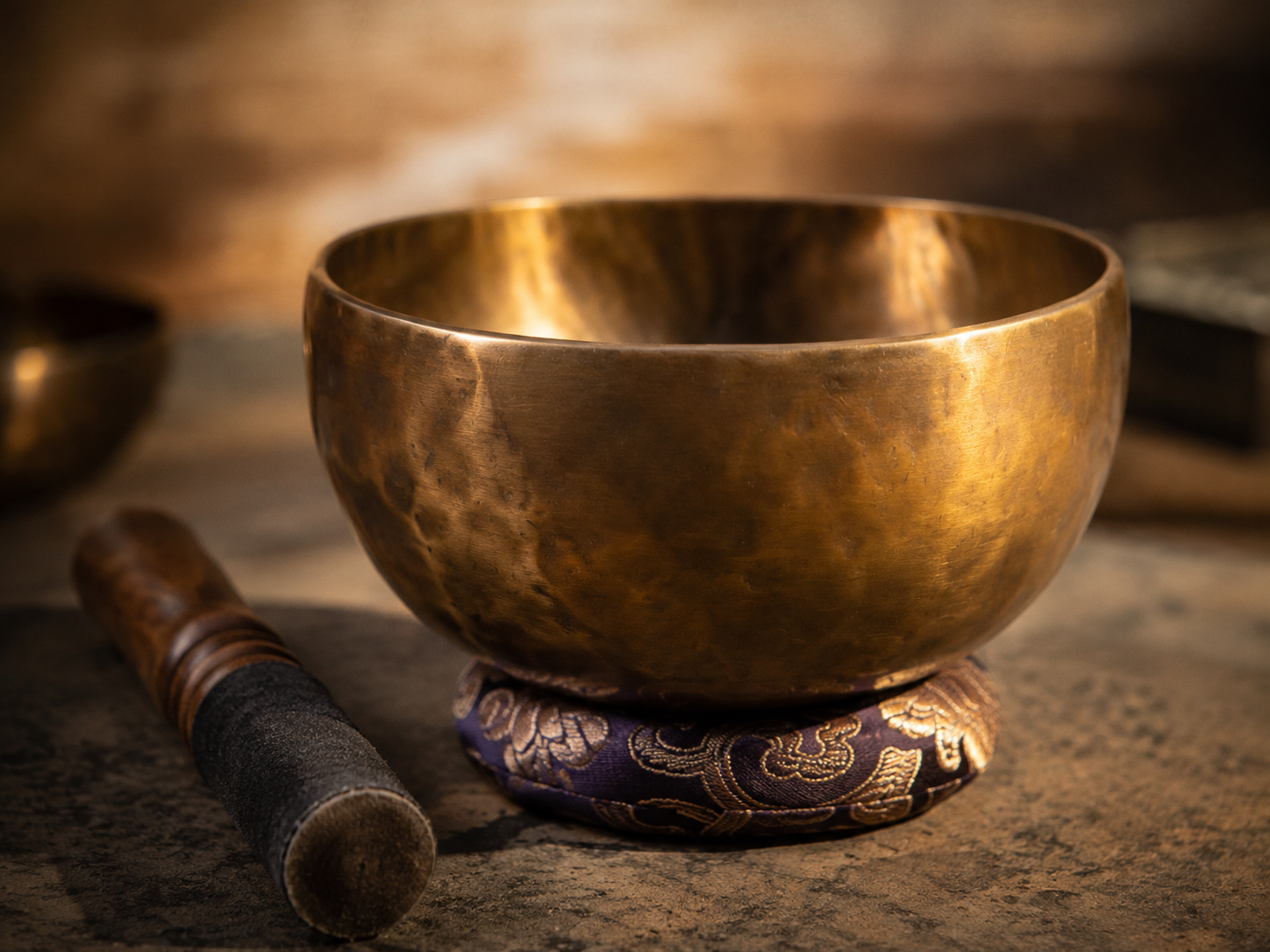 Close-up of a hand-forged bronze singing bowl with mallet and cushion, illustrating how sustain, resonance and craftsmanship reveal quality.
